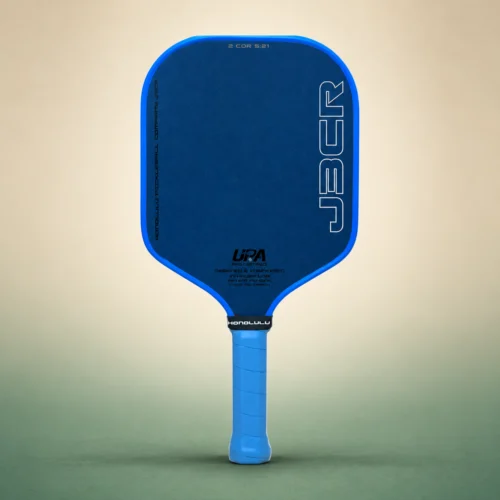 Honolulu J3CR Crystal Blue Endurance 16mm Pickleball Paddle, front view on a sand and green studio background Honolulu J3CR Crystal Blue Endurance 16mm Pickleball Paddle, front view
