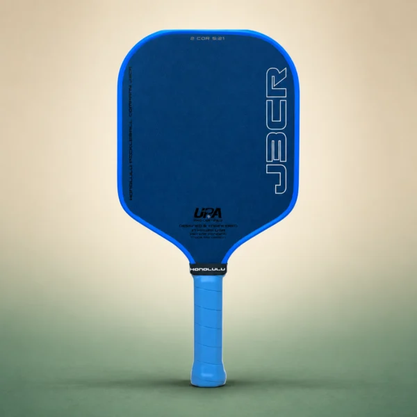 Honolulu J3CR Crystal Blue Endurance 16mm Pickleball Paddle, front view on a sand and green studio background Honolulu J3CR Crystal Blue Endurance 16mm Pickleball Paddle, front view